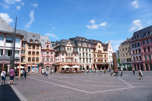 Mainz, Germany - May 27, 2019: People are sitting outside of cafes in the market square with the Heunensaeule on May 27, 2019 in Mainz...