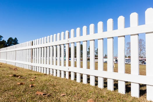 Boundary three feet wood white fence boundary across grass field blue sky day