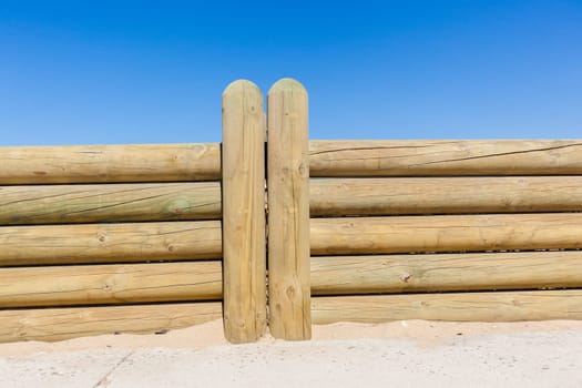 Wood poles low boundary fence wall decor outdoors closeup photo against blue sky