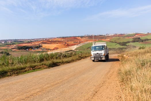 Industrial construction site overlooking large project expansion with graders,excavators,cranes machines into countryside sugarcane fields expanding earthworks infrastructure.
