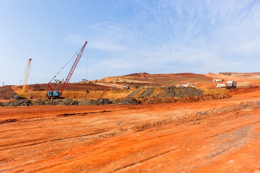 Industrial construction site overlooking large project expansion with graders,excavators,cranes machines into countryside sugarcane fields expanding earthworks infrastructure.