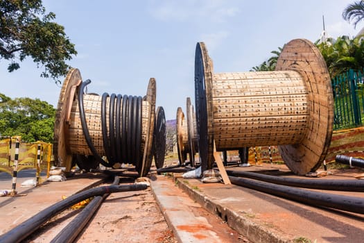 Electrical new high voltage cables on large wood drums been installed in underground Trenches industrial construction project.