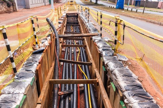 Electrical new high voltage cables on large wood drums been installed in underground Trenches industrial construction project.