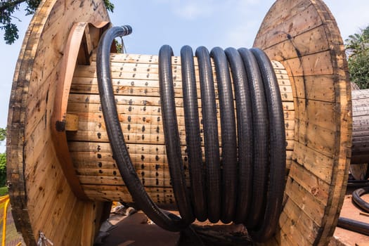 Electrical new high voltage cables on large wood drums been installed in underground Trenches industrial construction project.