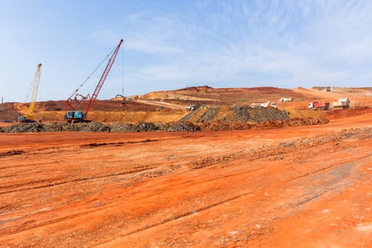 Industrial construction site overlooking large project expansion with graders,excavators,cranes machines into countryside sugarcane fields expanding earthworks infrastructure.