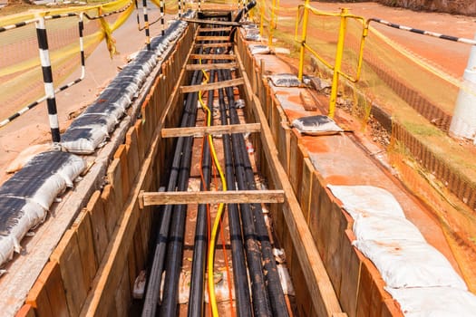 Electrical new high voltage cables on large wood drums been installed in underground Trenches industrial construction project.