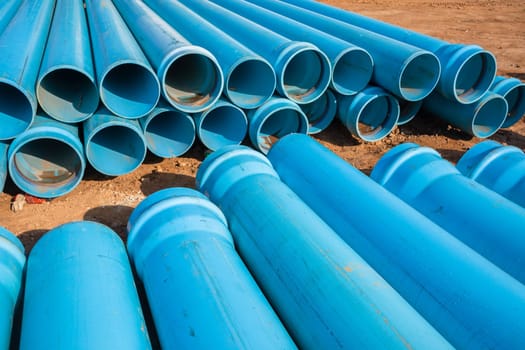 Construction blue plastic nylon pipes  stack on building site for plumbing infrastructure earthworks