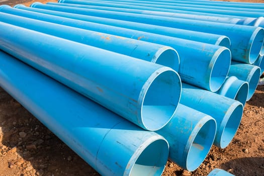 Construction blue plastic nylon pipes  stack on building site for plumbing infrastructure earthworks