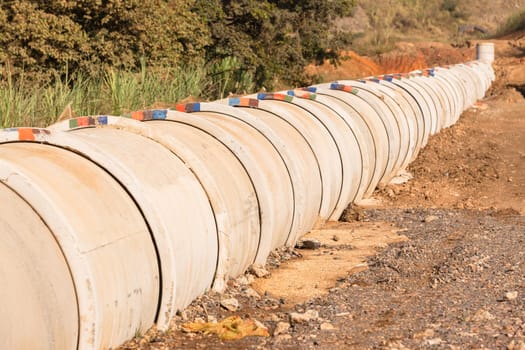 New concrete pipeline for waste sewerage water through countryside landscape vegetation.
