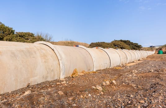 New concrete pipeline for waste sewerage water through countryside landscape vegetation.