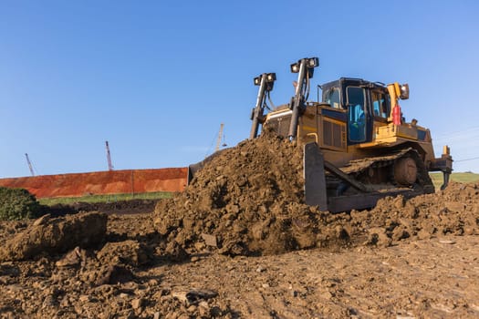 Construction industrial earthworks landfill dozer machine scoop bucket moving sand stones closeup abstract.