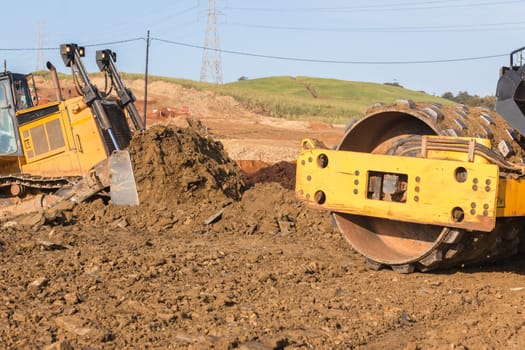 Construction industrial earthworks landfill compactor machine vibration leveling sand stones closeup abstract.
