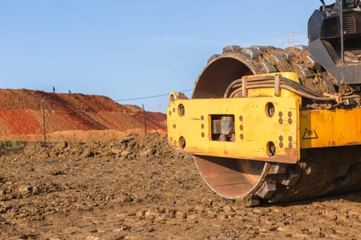 Construction industrial earthworks landfill compactor machine vibration leveling sand stones closeup abstract.