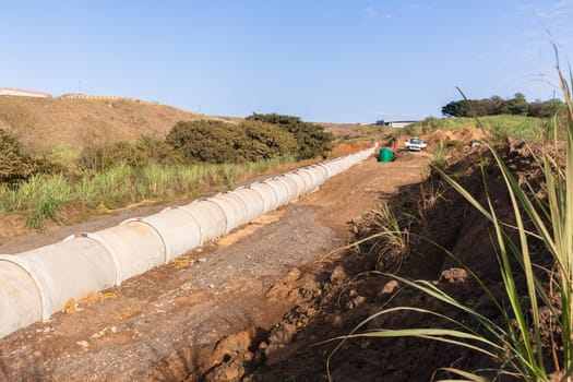 New concrete pipeline for waste sewerage water through countryside landscape vegetation.