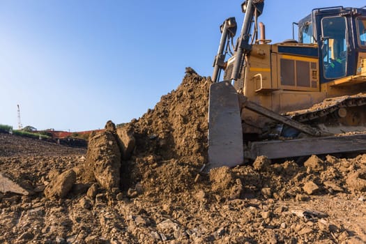 Construction industrial earthworks landfill dozer machine scoop bucket moving sand stones closeup abstract.