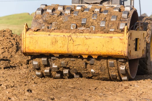 Construction industrial earthworks landfill compactor machine vibration leveling sand stones closeup abstract.