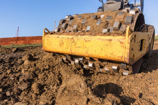 Construction industrial earthworks landfill compactor machine vibration leveling sand stones closeup abstract.