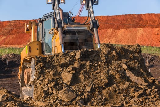 Construction industrial earthworks landfill dozer machine scoop bucket moving sand stones closeup abstract.