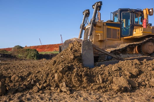 Construction industrial earthworks landfill dozer machine scoop bucket moving sand stones closeup abstract.