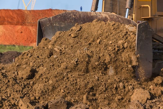 Construction industrial earthworks landfill dozer machine scoop bucket moving sand stones closeup abstract.