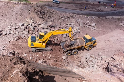 Industrial excavator machine loading construction truck vehicle heavy rock earthworks.