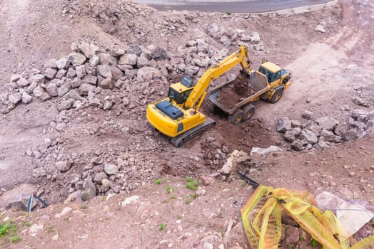 Industrial excavator machine loading construction truck vehicle heavy rock earthworks.