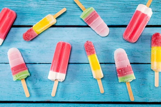 Colorful fruit ice cream stick look fresh to eat placed on a blue vintage wooden floor