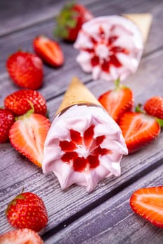 Ice cream cones with strawberries on a vintage wooden table summer. Focus on ice cream.