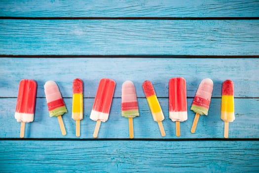 Colorful fruit ice cream stick look fresh to eat placed on a blue vintage wooden floor