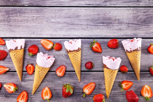 Ice cream cones with strawberries on a vintage wooden table summer. Focus on ice cream.