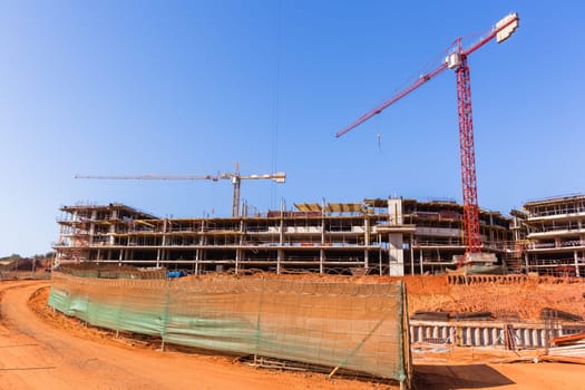 Building construction site industrial cranes concrete levels earthworks halfway apartment housing project.