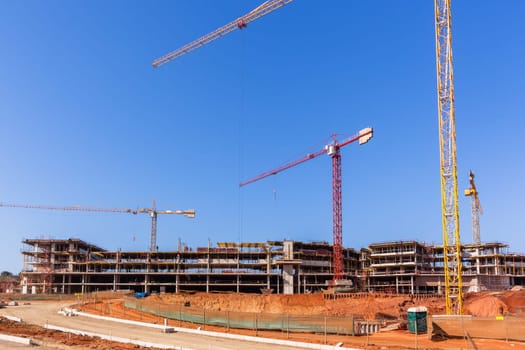 Building construction site industrial cranes concrete levels earthworks halfway apartment housing project.