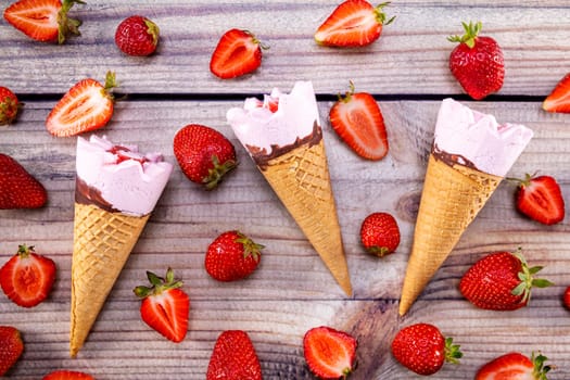 Ice cream cones with strawberries on a vintage wooden table summer. Focus on ice cream.