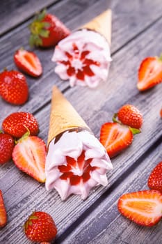 Ice cream cones with strawberries on a vintage wooden table summer. Focus on ice cream.