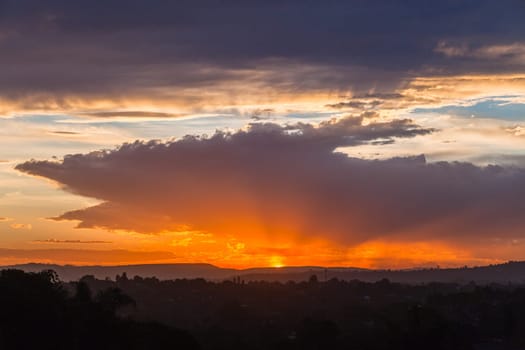 Sunset sundown clouds color contrasts over countryside hills homes a scenic landscape