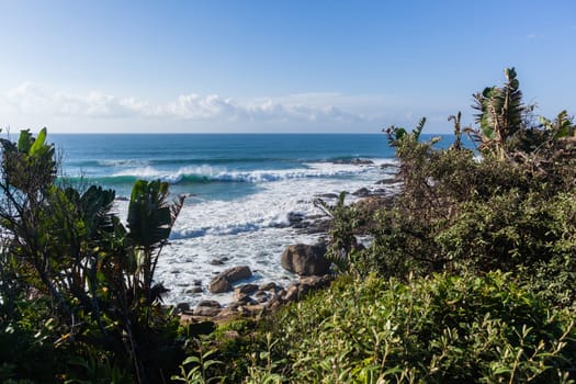 Ocean blue waves crashing along rocky scenic summer coastline landscape.
