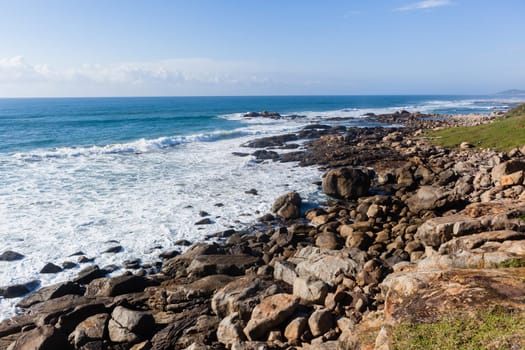 Ocean blue waves crashing along rocky scenic summer coastline landscape.
