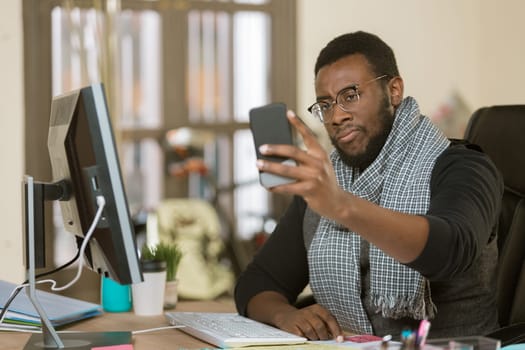 Skeptical professional man in a creative office using his mobile device