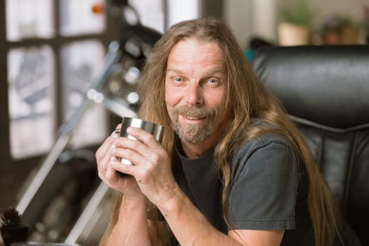Happy man at his desk with a coffee and motorcycle in the background