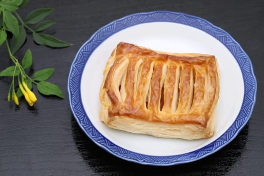Fresh apple pie on a plate on black background