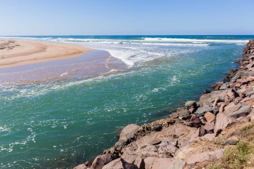 Beach river-mouth ocean waves along rocky coastline scenic summer landscape.