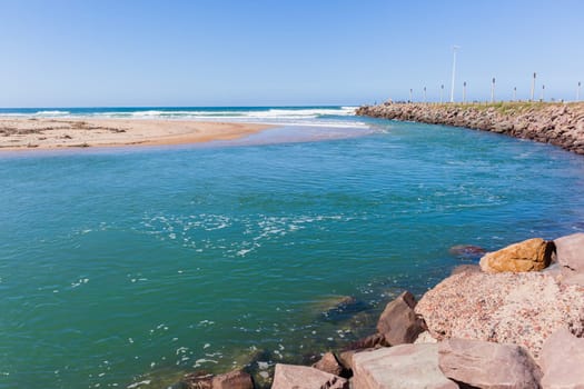 Beach river-mouth ocean waves along rocky coastline scenic summer landscape.