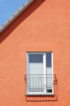 The roof edge and a window railing of a residential building cast shadows...