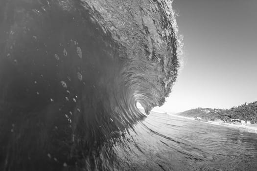 Ocean swimming closeup water photo inside hollow crashing wave black and white contrasts.