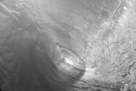 Ocean swimming closeup water photo inside hollow crashing wave black and white contrasts.