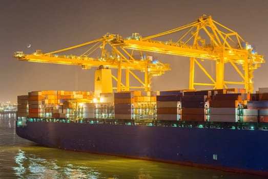 Tanker, cranes and containers at industrial sea port at night. Barcelona, Spain