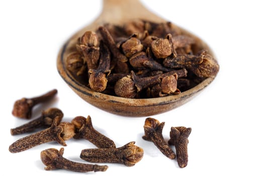 Clove spice on a wooden spoon with a scattering on a white table