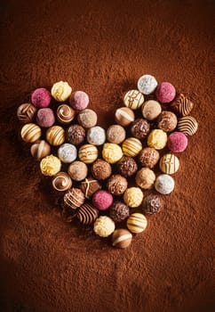 Romantic heart shaped chocolate still life on a background of cocoa powder with delicious handmade round decorated candy