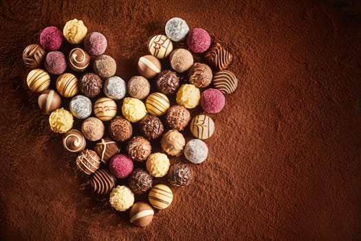 Valentines chocolate assortment in a heart shaped still life on a bed of cocoa powder with copy space for your greeting