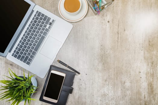 Top view of business desk with laptop, mobile phone, coffee, potted plant, notebook and business accessories on the office